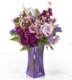 Purple roses and lilies with greens in a purple vase
