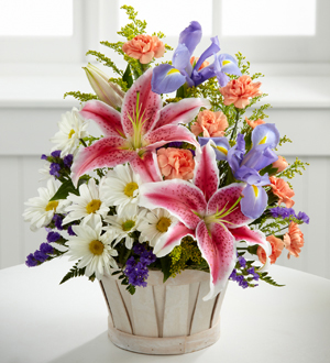 stargazer lilies with irises and daises in a round basket