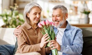 A man hands a woman a pink bouquet on Valentine's Day