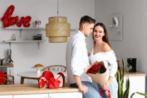 A woman hugs a man as she holds a bouquet of roses that he gave to her.