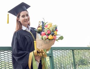 Happy graduate with flower bouquet in hand
